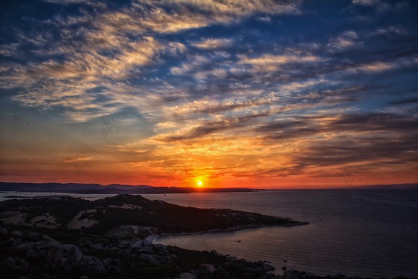 Cala di Trana beach, silky clouds and a breathtaking sunset on the North coast of Sardinia overlooking the Bocche di Bonifacio